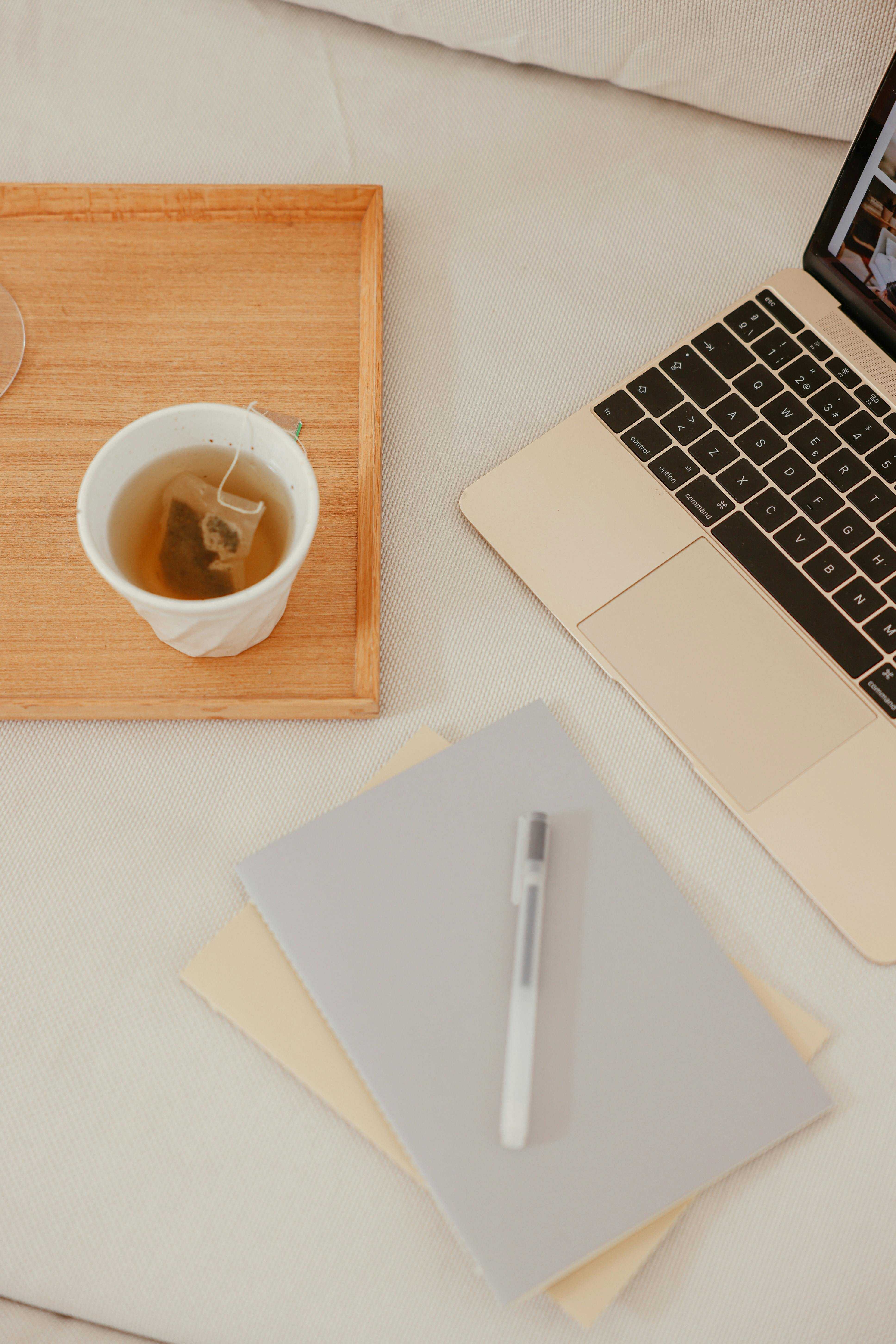 Tea, notepad, and laptop on a desk in a co-working space.